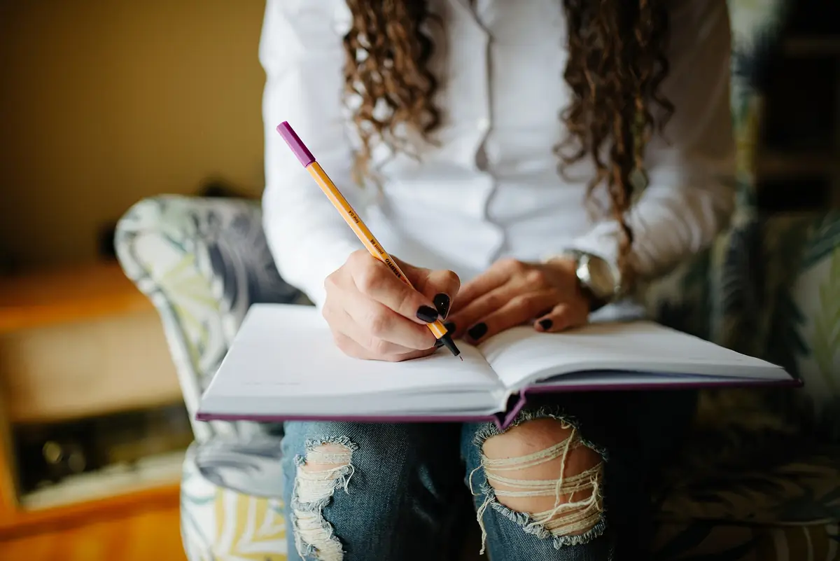 Close-up of a woman's hands writing notes in her planner